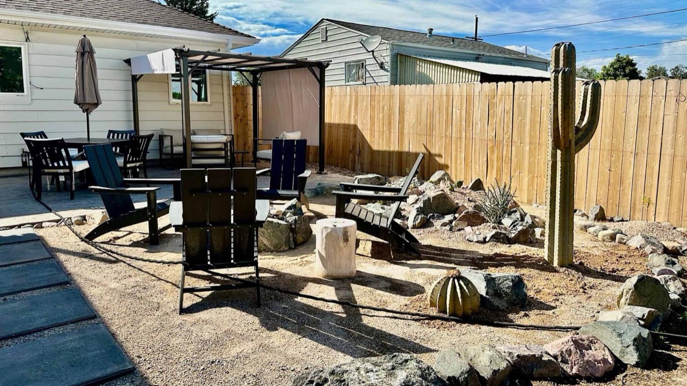 Backyard xeriscape with a decomposed granite seating area, boulders, and a wood privacy fence