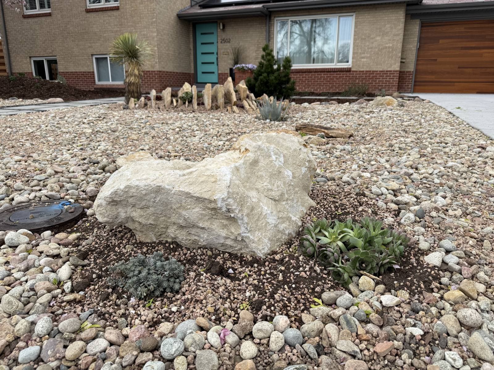 Rock groundcover, a quarried sandstone boulder, and succulents on the South Winona xeriscape by Xeris Landscaping